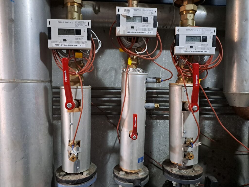 Trois tuyaux gris, avec des vannes rouges et des files, sont alignés surmentés de boitié blanc avec un écran affichants des valeurs.  - Agrandir l'image, fenêtre modale